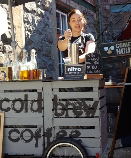 Lucia Beattie, Co-Owner of Nitro Coffee Co pouring cold brew coffee from a keg.